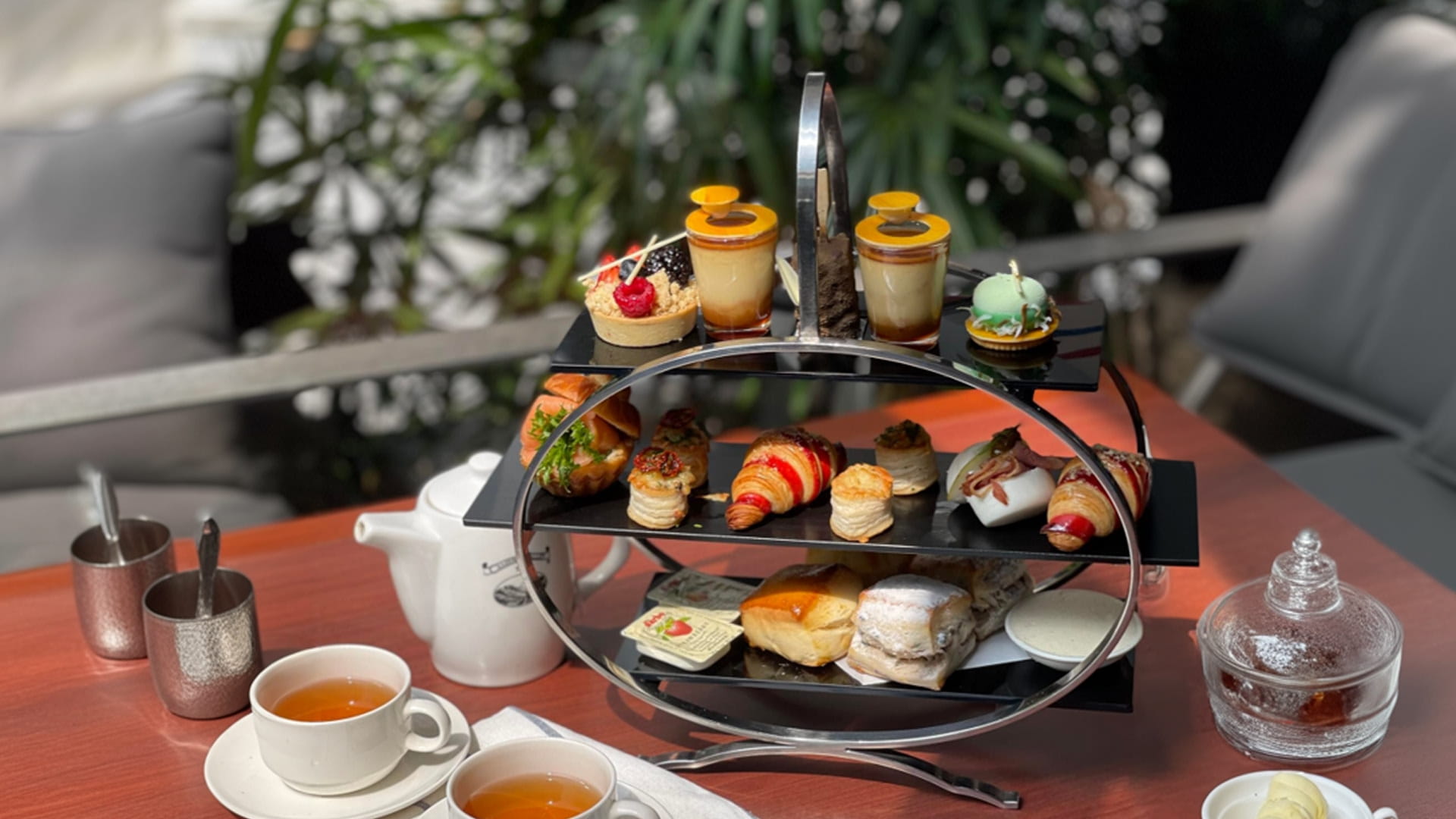 A three tier platter of sweets and savouries placed on a table for high tea 