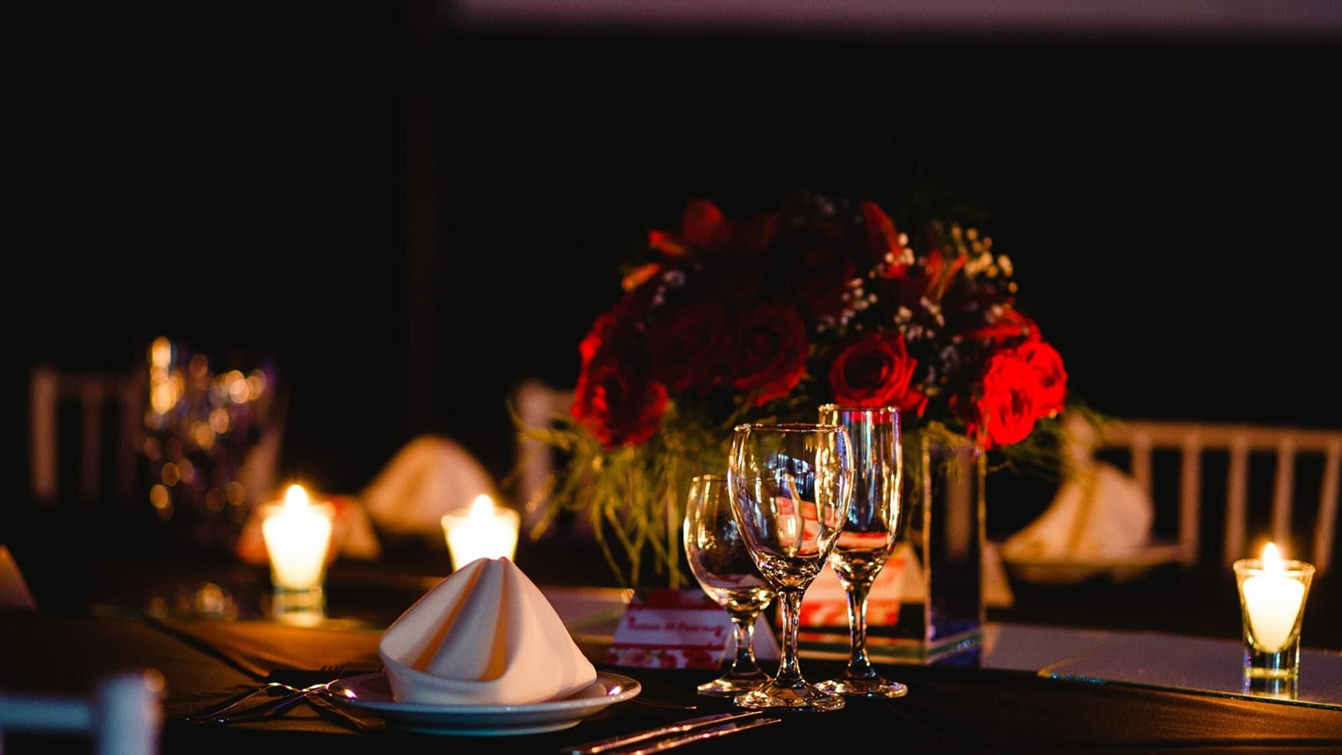 A romantic dinner setting with red roses as a centerpeice 